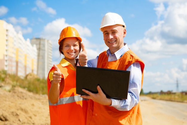 Travailleurs de la construction, hommes et femmes, regardant un ordinateur portable