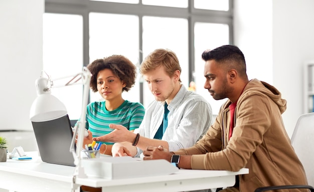 Photo des travailleurs créatifs heureux avec des ordinateurs portables au bureau