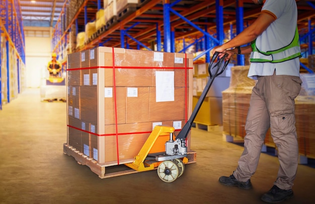 Travailleurs déchargeant des boîtes de colis sur des palettes dans un entrepôt de stockage