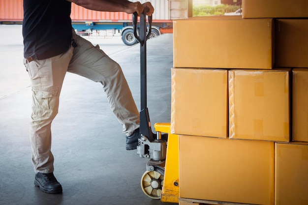 Photo travailleurs déchargeant des boîtes d'emballage sur des palettes dans l'entrepôt logistique d'entrepôt de fournitures de distribution