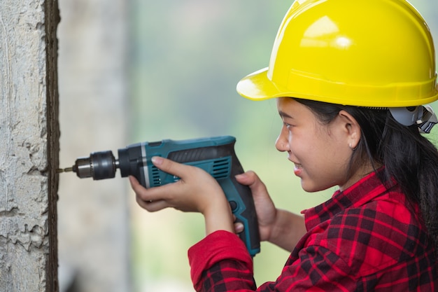 Travailleurs détenant une perceuse électrique en chantier, concept de la fête du travail