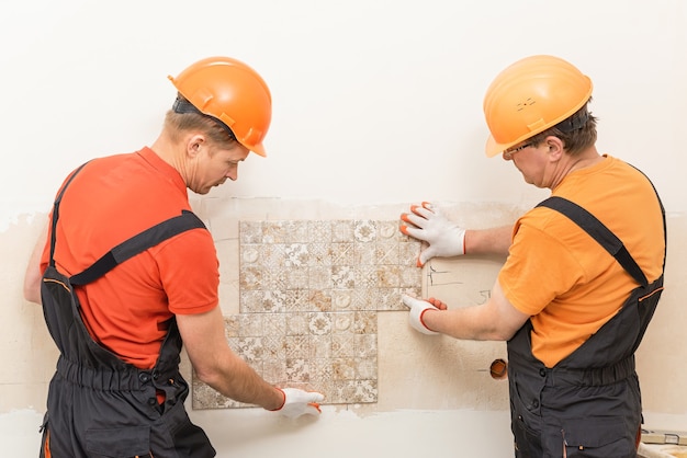 Les travailleurs essaient le carreau de céramique sur le mur