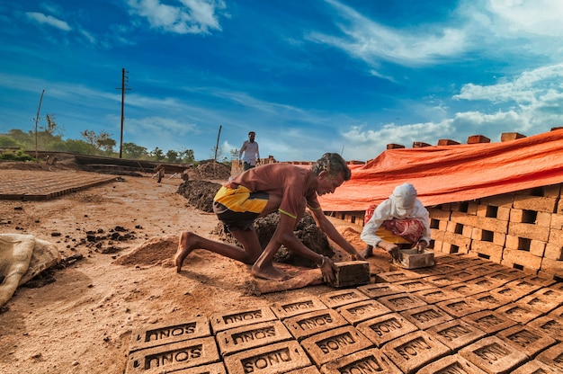 Travailleurs indiens fabriquant des briques d'argile à la main dans l'usine ou sur le terrain.