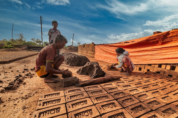 Travailleurs indiens fabriquant des briques d'argile à la main dans l'usine ou sur le terrain.