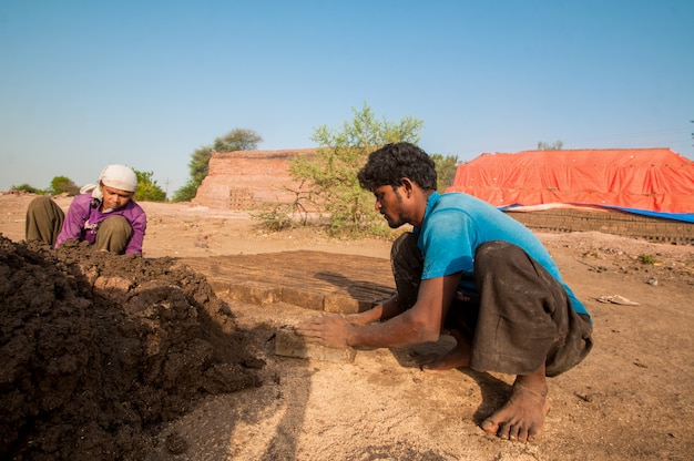 Les travailleurs indiens fabriquant des briques traditionnelles à la main dans l'usine de briques