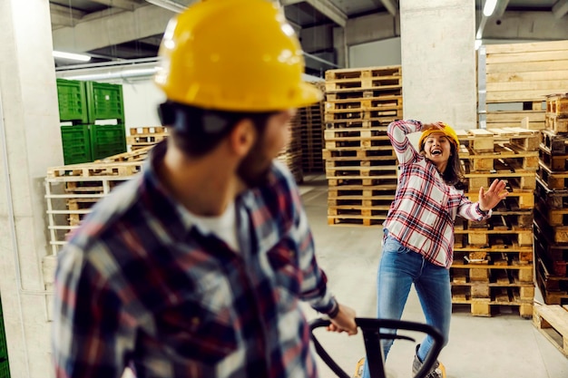 Travailleurs ludiques s'amusant au travail, ils jouent avec un chariot élévateur