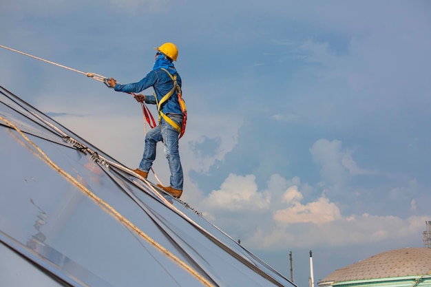 Travailleurs masculins sécurité de la hauteur d'accès à la corde se connectant avec un harnais de sécurité à nœud, systèmes d'arrêt de chute de toit et de point d'ancrage de retenue de chute prêts à monter, dôme de réservoir d'huile de chantier