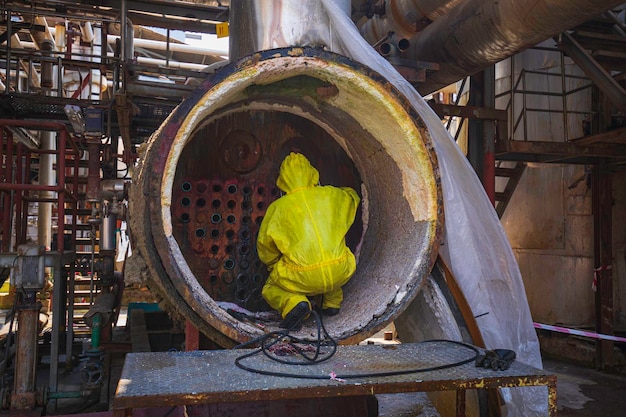 Les travailleurs masculins utilisent des jets d'eau à haute pression pour nettoyer les éclaboussures de la saleté des chaudières à tubes dans les zones industrielles ou le soufre des matières dangereuses toxiques