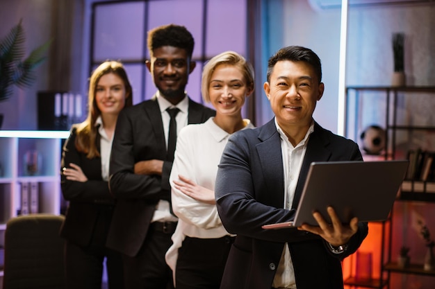 Travailleurs multiethniques heureux de l'entreprise debout dans une rangée dans un bureau créatif posant devant la caméra