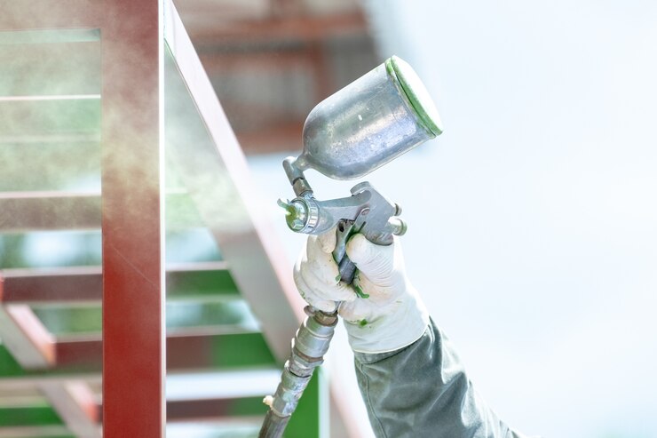 Travailleurs qui pulvérisent de la peinture sur du métal