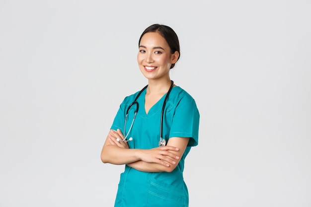 , travailleurs de la santé, concept de pandémie. Professionnel confiant, souriant femme médecin asiatique, infirmière en gommage avec stéthoscope pour examens, bras croisés