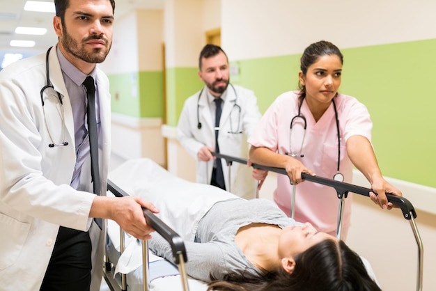 Photo des travailleurs de la santé masculins et féminins tendus précipitent le patient sur une civière dans le couloir de l'hôpital