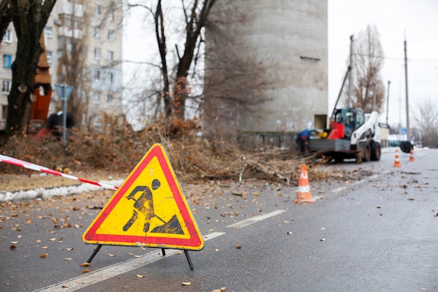 Les travailleurs des services publics municipaux coupent des branches d'arbres, bloquant la rue