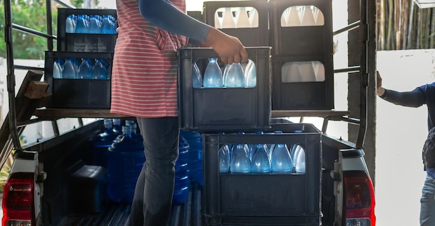 Les travailleurs soulèvent des bouteilles d'eau potable bleues dans des caisses à l'arrière d'un camion de transport