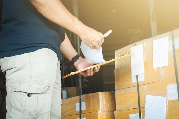 Travailleurs tenant un presse-papiers faisant de la gestion des stocks des boîtes d'emballage de l'entrepôt de stockage