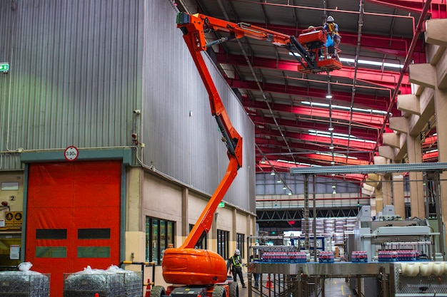 Travailleurs travaillant sur le chantier de construction de la nouvelle industrie de l'usine pour nacelle élévatrice qui va jusqu'au toit supérieur