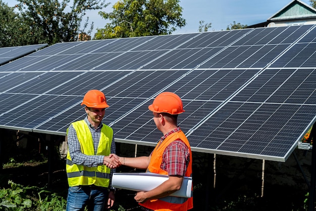 Travailleurs vérifiant le travail de la station de panneaux solaires et en discutant avec une tablette