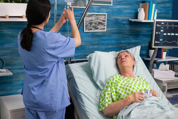 Une travailleuse assistante injecte un traitement médical dans un sac d'égouttement intraveineux