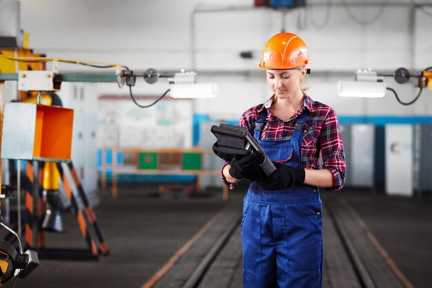 Travailleuse avec des chapeaux durs travaillant à l'usine industrielle et à la recherche dans le contrôleur industriel