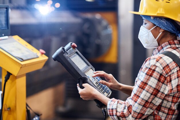 Travailleuse dans un respirateur et un casque touchant l'écran du dispositif de commutation