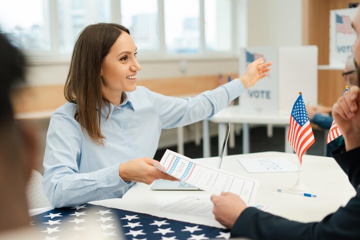 Photo une travailleuse latine souriante tenant un bulletin de vote pointant vers quelque chose alors qu'elle est assise à la table d'enregistrement