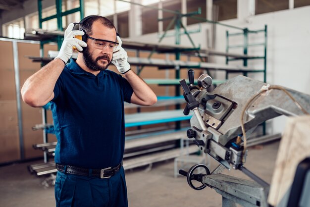 Travailleuse de machine à scier à ruban mettant des cache-oreilles protecteurs