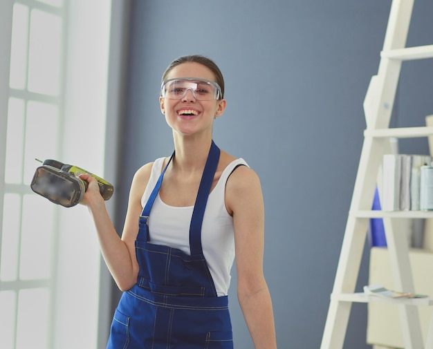 Travailleuse avec perceuse debout dans une nouvelle maison