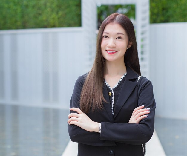 Travailleuse professionnelle asiatique en costume noir tout en marchant à l'extérieur pour travailler au bureau en ville.