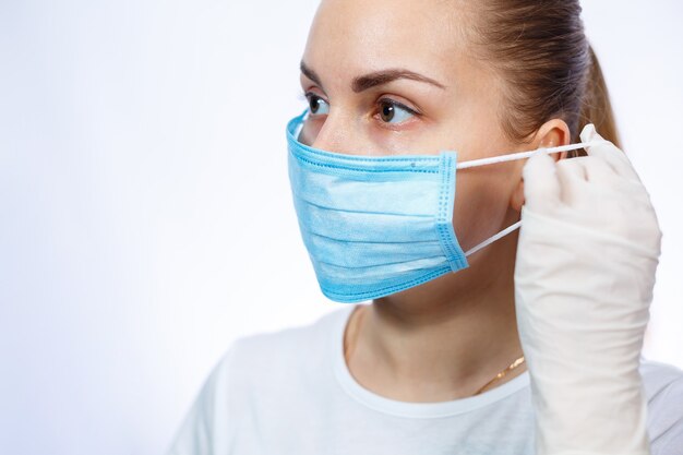 Une travailleuse de la santé montre comment porter un masque chirurgical médical de protection contre le virus. Isolé sur fond blanc