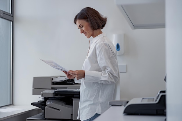 Travailleuse souriante numérisant un document sur une photocopieuse dans un bureau moderne