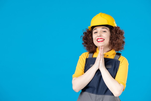 Travailleuse en uniforme jaune et casque sur bleu