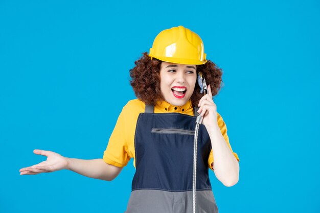 Travailleuse en uniforme jaune tenant une douche sur bleu