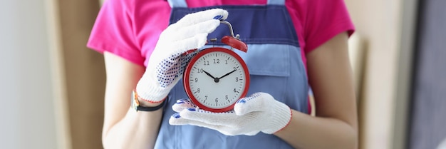 Travailleuse en uniforme tenant un rappel d'horloge rouge pour terminer le travail à temps