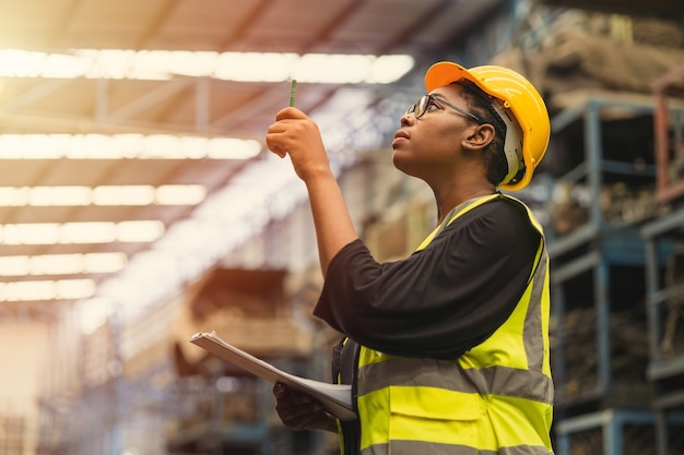 Travailleuses professionnelles africaines noires travaillant le compte vérifiant le contrôle des stocks de production d'inventaire dans l'industrie de l'usine commerciale entrepôt waring ingénieur costume et casque pour la sécurité