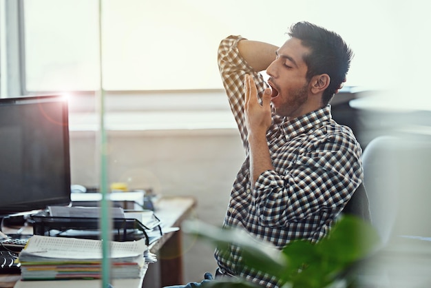 Les travaux font vraiment des ravages Photo recadrée d'un homme d'affaires bâillant tout en travaillant à son bureau