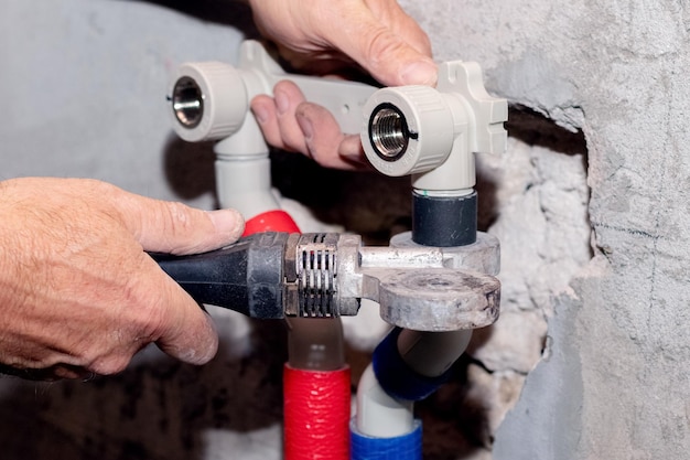 Travaux d'installation de chauffage ou de plomberie Le maître connecte des tuyaux en plastique avec un fer à souder