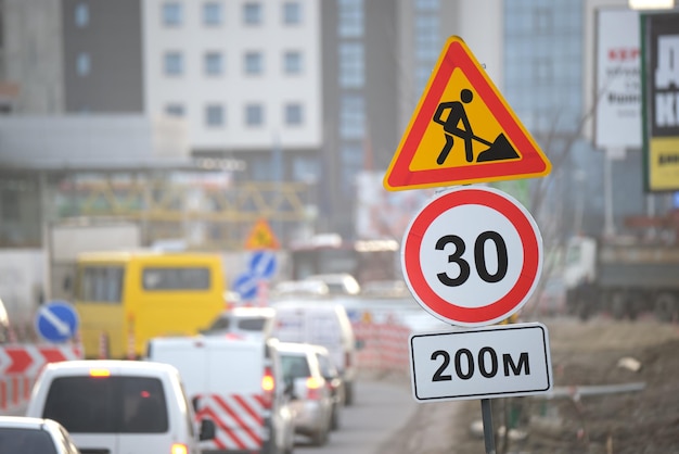 Travaux routiers avertissant les panneaux de signalisation des travaux de construction dans la rue de la ville et des voitures en mouvement lent