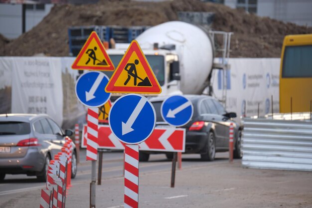 Travaux routiers avertissant les panneaux de signalisation des travaux de construction dans la rue de la ville et des voitures en mouvement lent