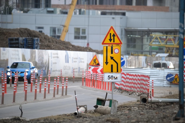 Travaux routiers avertissant les panneaux de signalisation des travaux de construction dans la rue de la ville et des voitures en mouvement lent