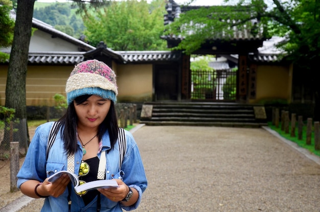 Traveller thai woman reading guide book for travel Nara city in garden of Todaiji Temple at Kansai region in Nara Japan