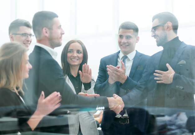 À travers le verre, les hommes d'affaires se rencontrent avec une poignée de main