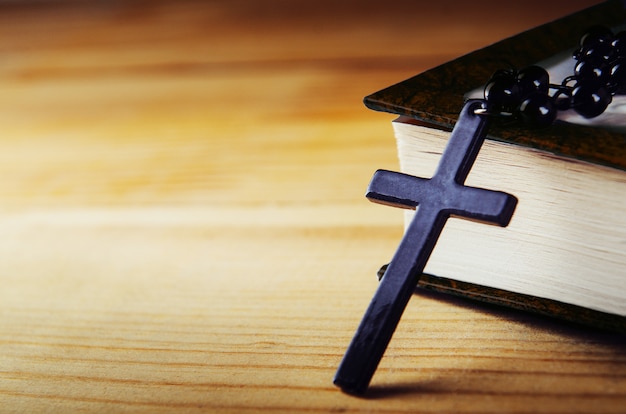 Traverser sur un fil avec des perles noires avec une bible sur une table en bois.