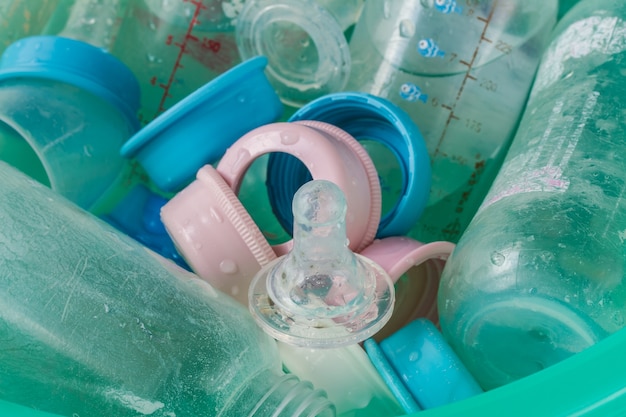 Photo des trayons et des bouteilles sales dans un seau de plastique bleu.