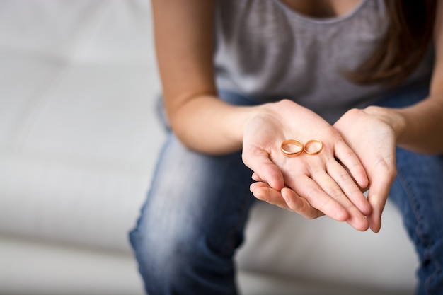 Être femme triste regarde la bague dans la paume devant lui, nostalgique d'un ancien mari, famille, mariage. Le concept de relation, de divorce.