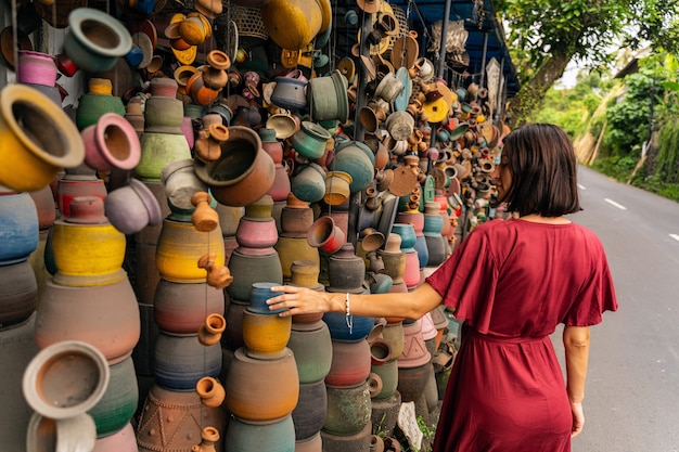 Être inspiré. Fille brune heureuse tournant la tête tout en regardant la poterie colorée pendant la marche