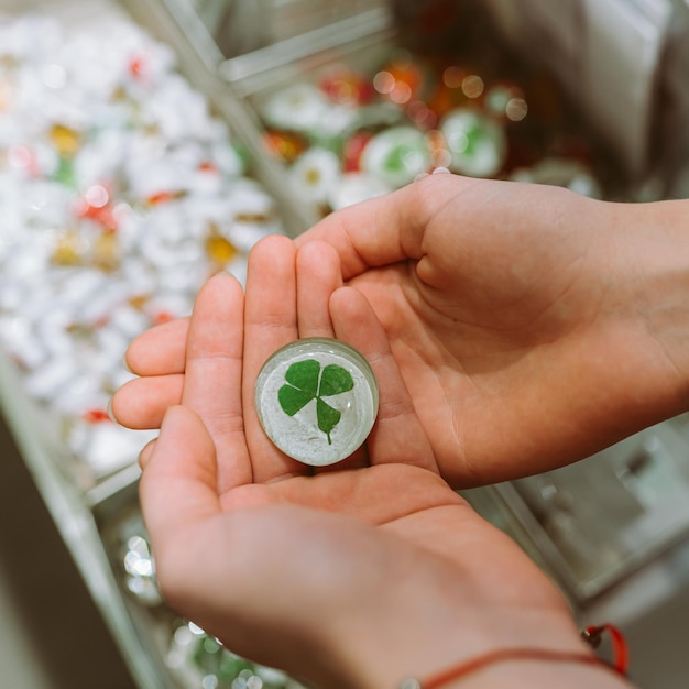 trèfle à quatre feuilles en porte-clés entre les mains d'une fille, talisman de bonne chance dans tous les efforts