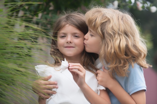 Étreindre et embrasser les enfants couple de petits enfants adorables enfants en plein air dans le parc d'été gros plan visage