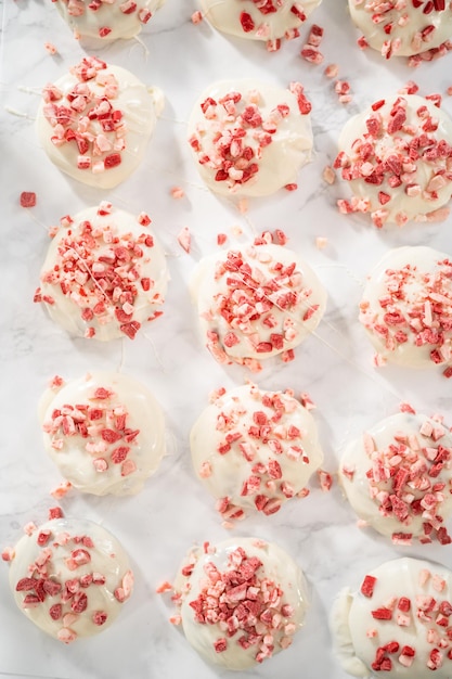 Tremper des biscuits au chocolat dans le chocolat blanc fondu pour préparer des biscuits au chocolat blanc à la menthe poivrée.