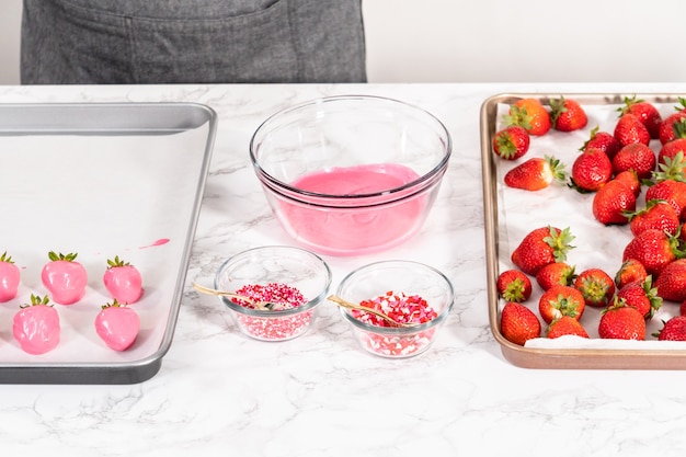 Tremper les fraises dans le chocolat fondu pour préparer des fraises enrobées de chocolat.