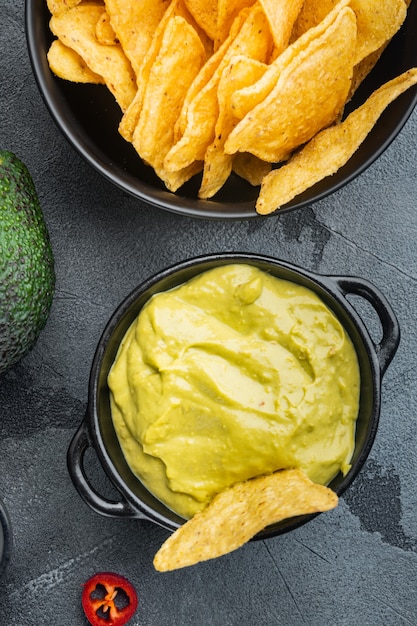 Trempette d'avocat crémeuse avec coriandre et citron vert dans un bol, sur table grise, vue de dessus ou mise à plat